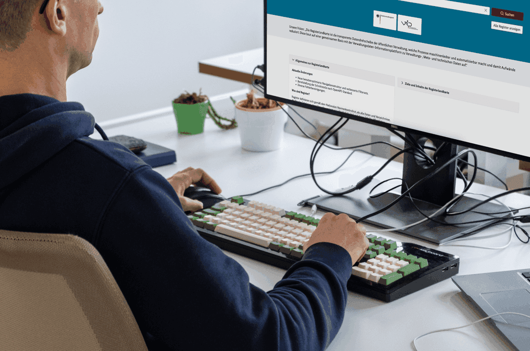 Ein Mann sitzt an einem Computer. Auf dem Bildschirm ist eine Webseite der Registermodernisierung geöffnet.